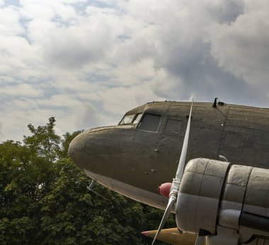 Part of an old World War II military aircraft. Background of sky and trees.