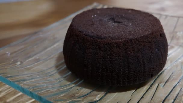 Azúcar powndered cae en un pequeño pastel de chocolate en la mesa de madera — Vídeos de Stock