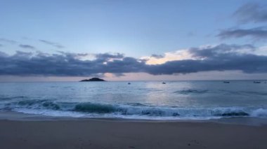 Mavi saatte deniz, ufukta küçük bir ada.