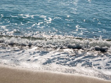 Sahildeki deniz dalgaları güneş ışığında parlıyor, huzur ve huzur kavramı.