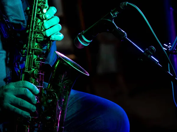 artist musician plays the saxophone illuminated by green light