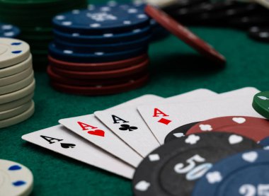 Poker masası, yeşil masada dört as ve bir yığın oyun fişi.