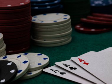 Poker masası, yeşil masada üç as ve bir yığın oyun fişi.