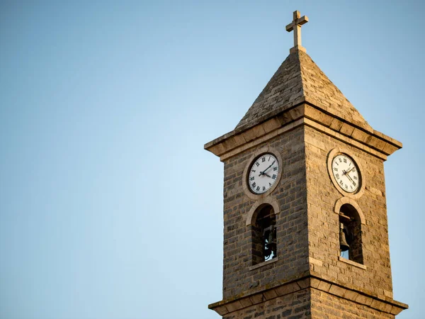 Ortaçağ İtalyan kilisesinin çan kulesi ve saatine sahip bir kulenin yan görüntüsü.