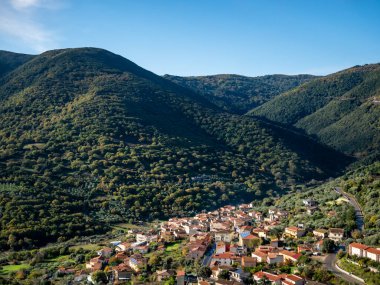 Yeşil tepeler ve mavi gökyüzü arkaplanı arasında inşa edilmiş küçük bir İtalyan kasabası.