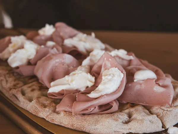 Mozarella ve mortadella ile kaplanmış tipik Pinsa Romana ile ahşap kesme tahtasını kapat