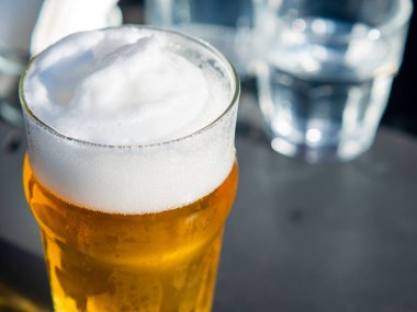 Lokanta masasında köpüklü bira bardağını kapat.
