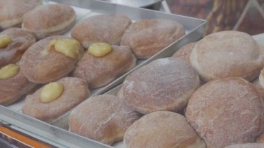 assortment of various cream-filled Berlin donuts for sale in a pastry shop