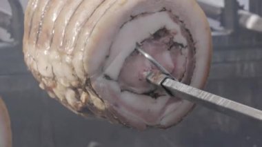 close-up shot of pork roll while roasting on hot coals. Roast Porchetta, a typical Italian dish of pork