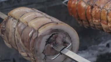 close-up shot of pork roll while roasting on hot coals. Roast Porchetta, a typical Italian dish of pork