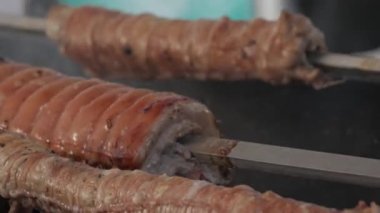 various types of pork roast meat on a metal skewer over the coals in a barbeque