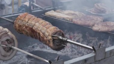 various types of pork roast meat on a metal skewer over the coals in a barbeque