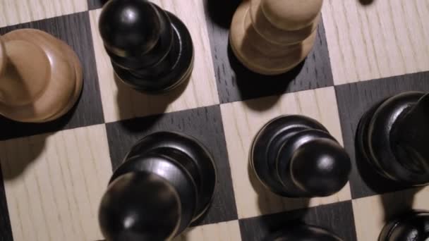 Rotierendes Schachbrett mit weißen und schwarzen Holzfiguren von oben — Stockvideo