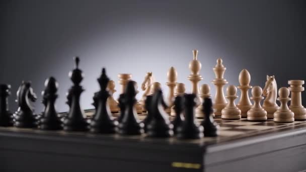 Rotating chessboard with lines of white and black wooden chess figures — Stock Video