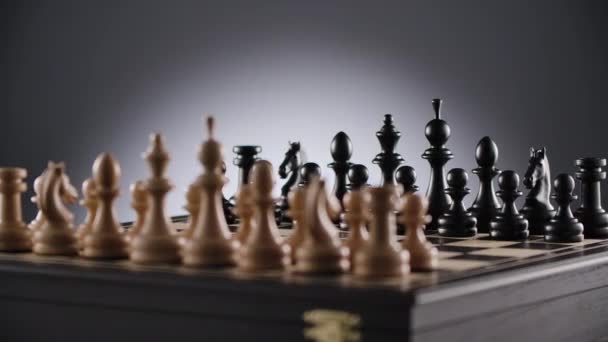 Rotating chessboard with lines of white and black wooden chess figures — Stock Video