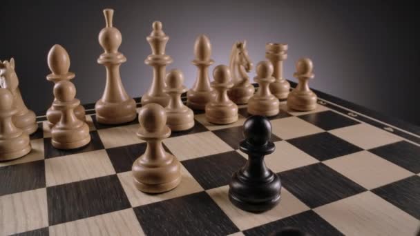 Roterande schackbräda med linjer av vita och svarta schackfigurer i trä — Stockvideo