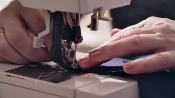 As mãos de mulheres cosem um tecido azul na máquina que cose Gráficos De Vetor