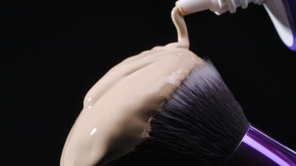 Бежевый фундамент наливается на щетку для макияжа — стоковое видео