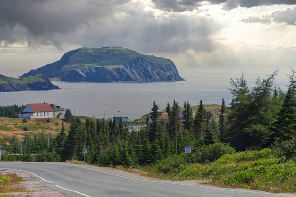 Road winding down to Tors Cove harbour with Fox Island on background, Newfoundland island, Canada — стоковое фото