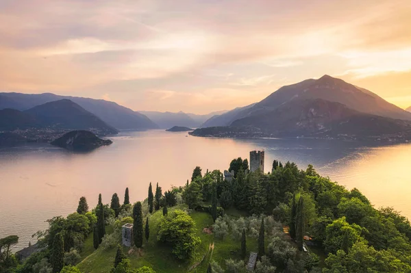 Vertical panoramic aerial view of Vezio Castle with Varenna village and mountains in background during summer sunset. Drone shot in Como lake. Varenna, Italy — Foto de Stock