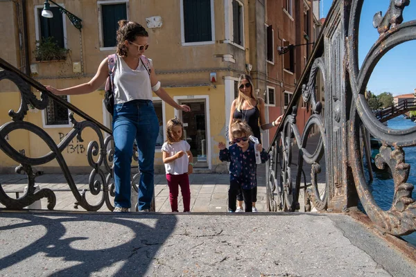 Venedik, İtalya - 27 Ağustos 2021 Venedik kanalları üzerinden köprüden geçen anneler ve küçük kızlar 