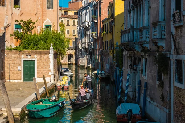 VENICE, İtalya - 27 Ağustos 2021: Gondol, tipik bir Venedik su kanalı üzerinde yelken açıyor.