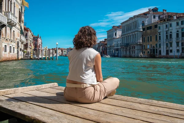 İtalya 'da Venedik kanalları karşısında meditasyon yapan genç bir kadın..