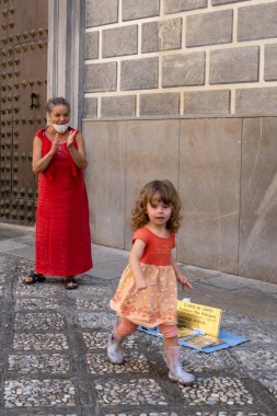 GRANADA, SPAIN - SEPTEMBER 25, 2021: View of beautiful little girl giving a coin to street artist in Granada.