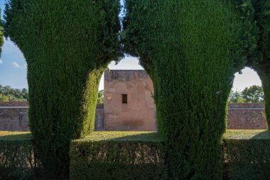 Building view between green arch of plants in Alhambra.