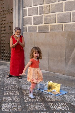 GRANADA, SPAIN - SEPTEMBER 25, 2021: View of beautiful little girl giving a coin to street artist in Granada.