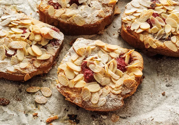 Bostock with the addition of almond cream (frangipane) and raspberries made of baked brioche slices, close up view. Traditional french sweet toast.