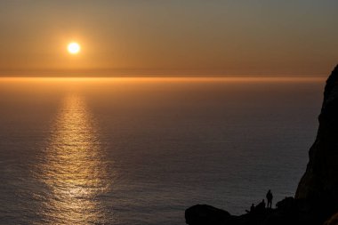 Kaçın, Norway - 2020 Nisan 20. Gün batımında Bird Island Runde 'da siluetteki insanlar.