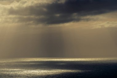 RUNDE, NORway - 2020 Mayıs 06. Okyanustaki kara bulutların arasından geçen güneş ışınları.