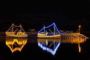 USTEINVIK, NORWAY 10 ARALIK. Geceleyin yılbaşı ışığı olan iki ahşap tekne..