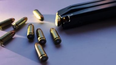 9mm kalibrelik parabellum mermileri, bir şarjör dolusu merminin yanında otlayan ışıkla izole edilmiş.