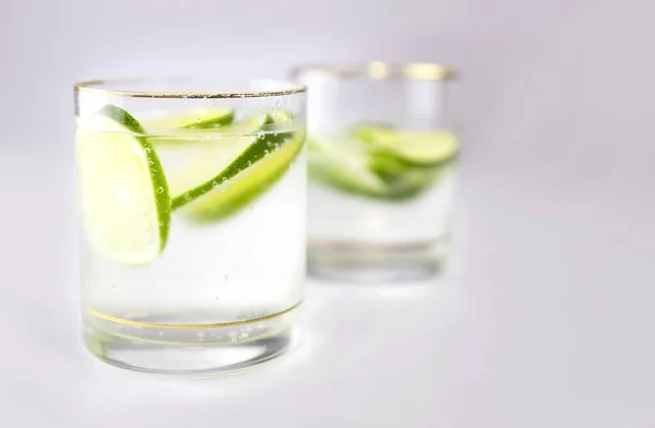 Bir bardağı köpüklü suyla ve birkaç dilim limonla dolduran çok sayıda baloncuk, sağlıklı ve ferahlatıcı içecek, gri arkaplan