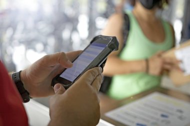 İnternetten alışveriş konsepti. Bir çalışan, teslimatı mobil bir cihaza kaydediyor. Arka planda tanınmayan bir kişi sevkiyatı topluyor.