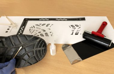 Bilimsel bir polis müfettişi, CSI, laboratuvarda, mürekkeple ayakkabı izlerinden örnekler alıyor.