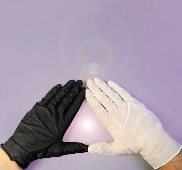 Hands with black and white gloves, united to form a triangle and in the center a soft luminous flash on a violet background, healing energy, triangular shaped energy field with plenty of copy space