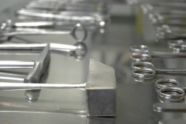 Paslanmaz çelik bir masaya odaklan, adli tıp aletleri açıkta, makas, neşter, çekiç, vs.