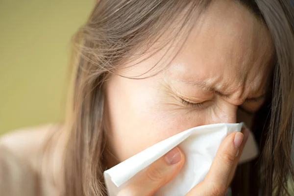 Having a cold or corona virus flu symptoms. Young woman with a an allergy sneezing into her handkerchief to prevent spread the disease for immunity