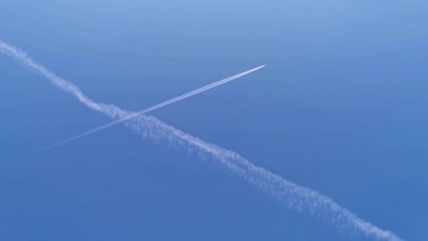 商業用飛行機は青い空を斜めにフレームに飛んでいます 飛行機の航空空港は雲を追跡します 白い航空会社は乗客を輸送し 青い空に白いコンクリートを引く — ストック動画