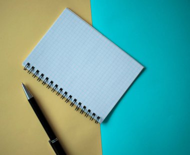 Ofis işyeri konsepti çok az. Sarı ve mavi arkaplanlı boş bir defter. Kopyalama alanı olan üst görünüm, düz yatay