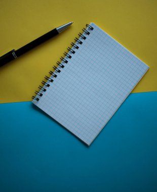Ofis işyeri konsepti çok az. Sarı ve mavi arkaplanlı boş bir defter. Kopyalama alanı olan üst görünüm, düz yatay