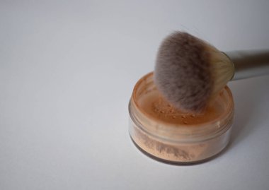 Beyaz arkaplanda makyaj fırçası ve yüz pudrası