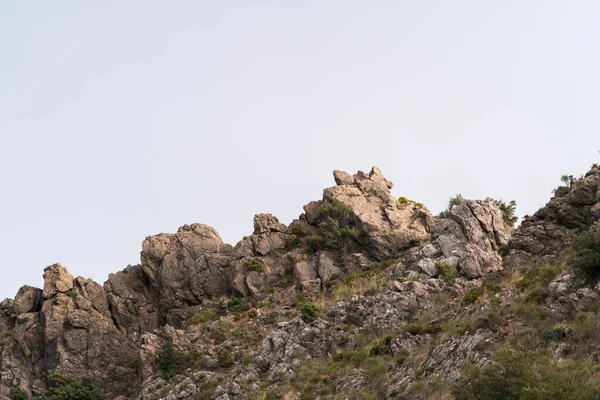Granada 'nın güneyindeki bir dağda kaya oluşumu, çalılar var ve gökyüzü bulutlu.