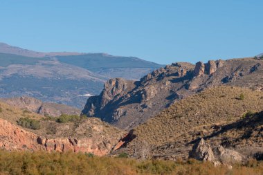 mountainous landscape in southern Spain, there are bushes and trees on the mountainside, the sky is clear