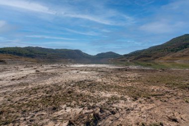 mountainous landscape in southern Spain, there are trees and bushes, there is a water reservoir, the sky is clear