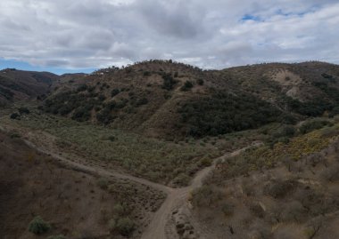 Granada 'nın güneyindeki dağda bir vadi, ağaçlar ve çalılar var, gökyüzünde bulutlar var.