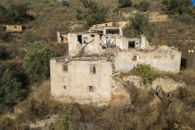 group of farmhouses in the south of Granada, there are trees and shrubs, it is a mountain area